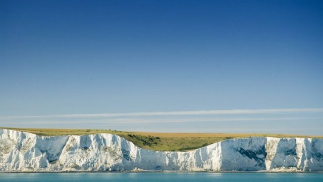 White cliffs of dover overlooking a blue sea viewed from a boat offshore