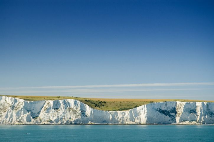 White cliffs of dover overlooking a blue sea viewed from a boat offshore